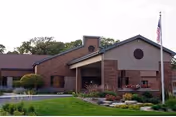 Exterior view of Highland Oaks senior living facility with brick facade and flag.