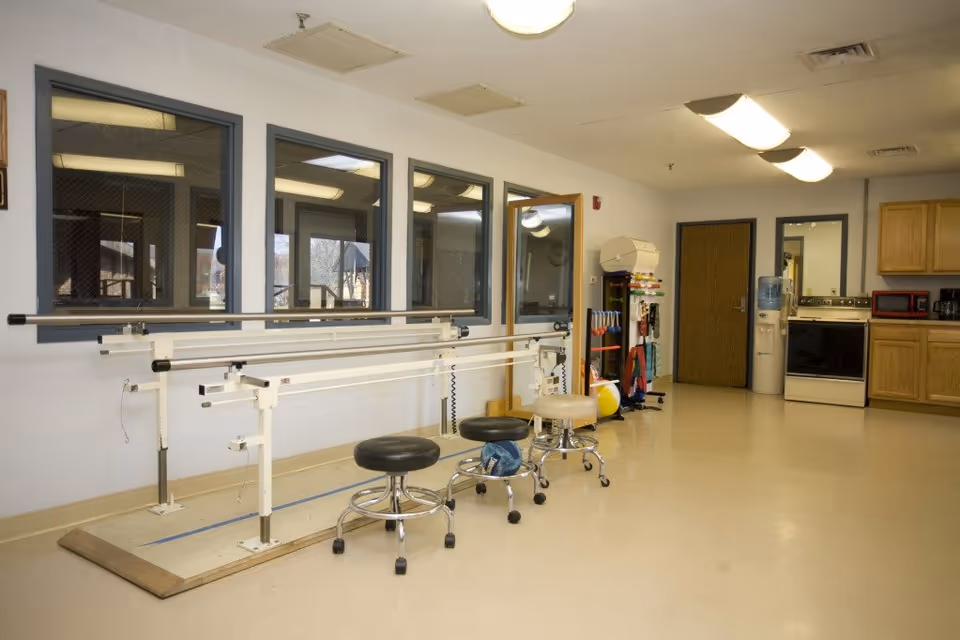Therapy room at Rolling Hills Healthcare Center featuring parallel bars and stools along wall.