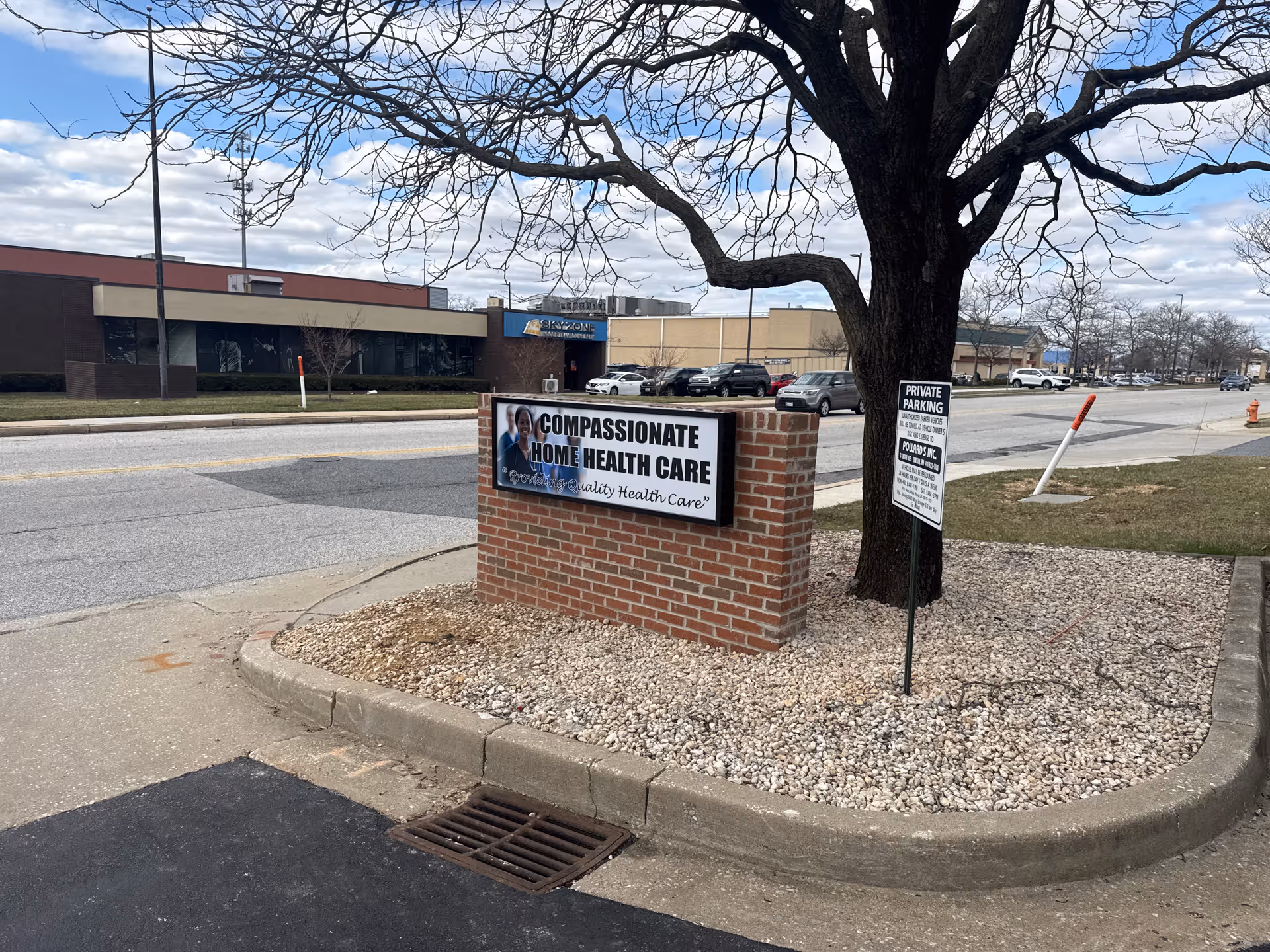 Exterior view of a brick sign for Compassionate Home Health Care along a street.