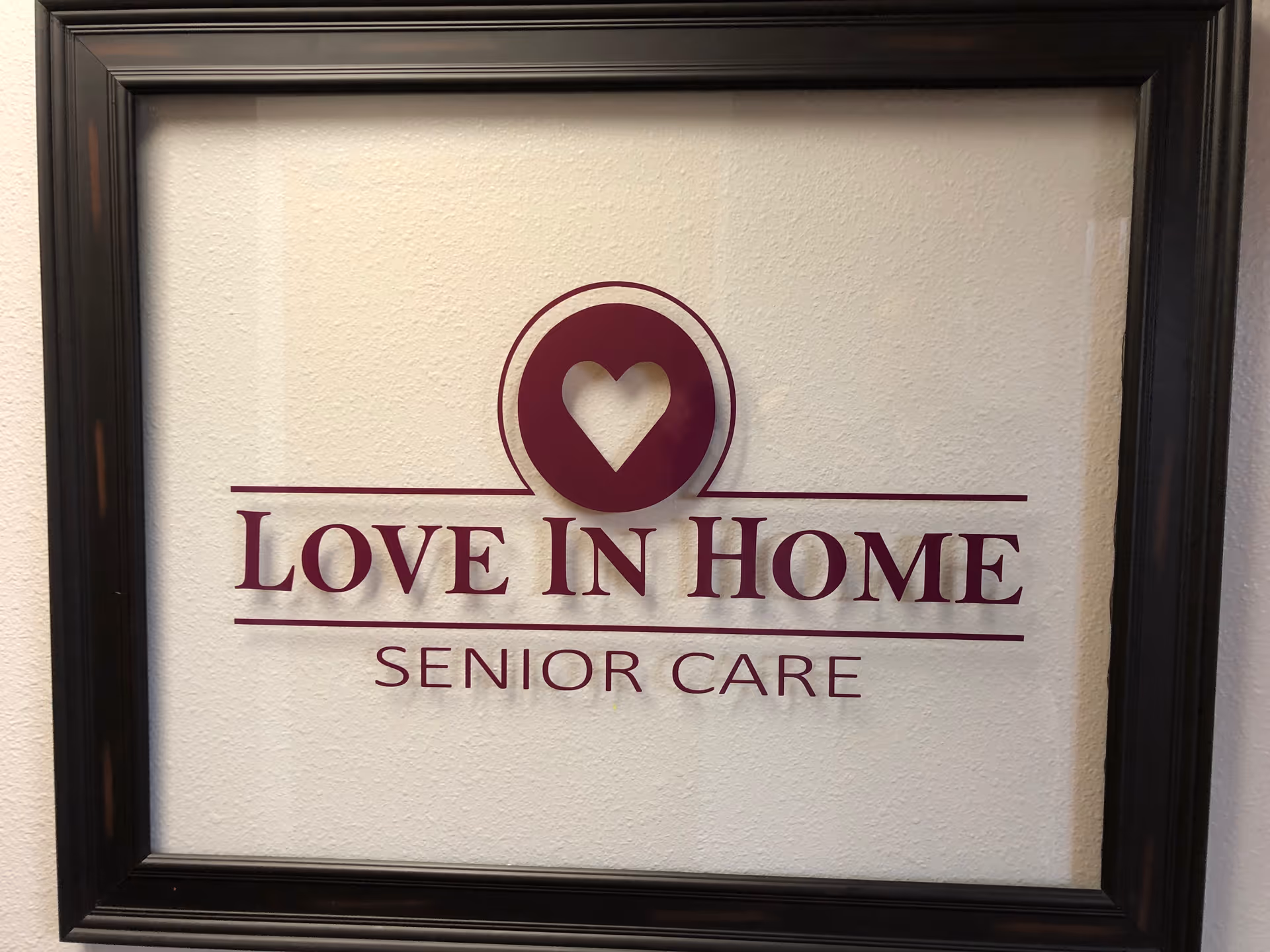 Framed wall sign displaying Love In Home Senior Care with a heart logo.