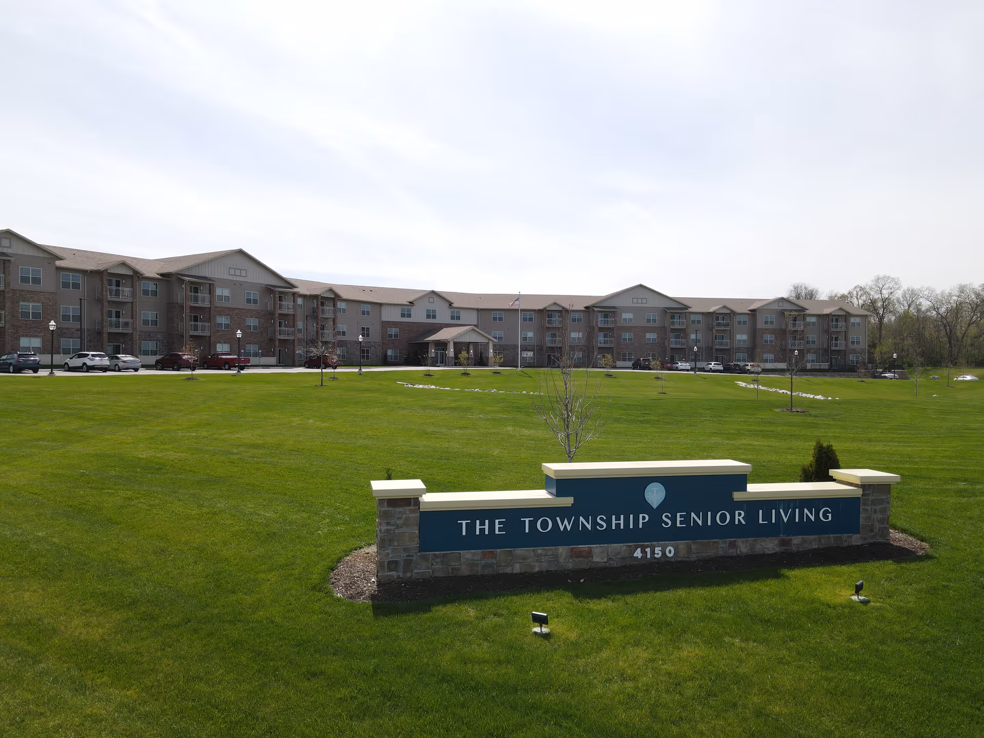 Wide exterior view of The Township Senior Living campus with front sign in foreground.