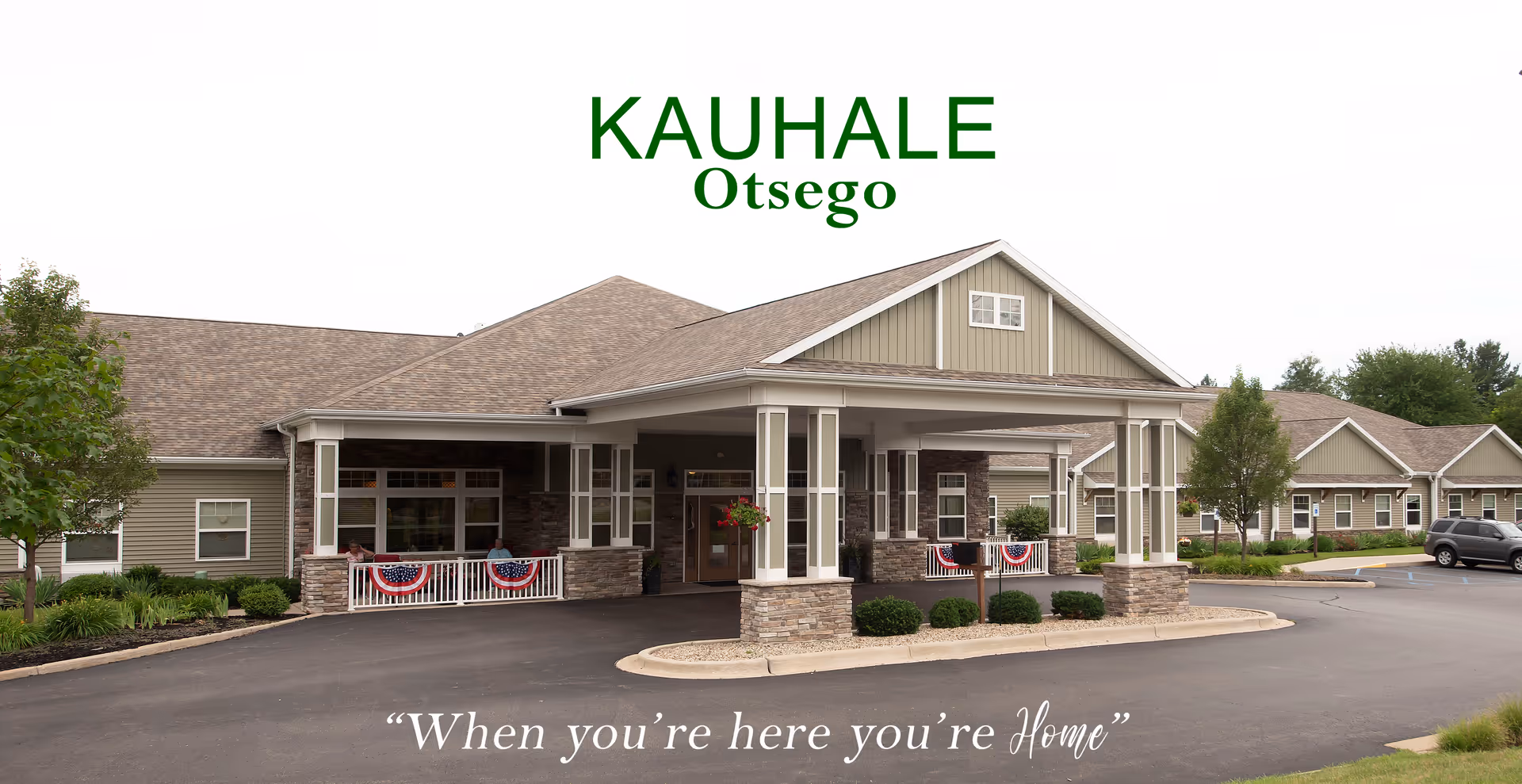 Exterior view of Kauhale Otsego senior living center with a porte-cochere entrance and landscaping.