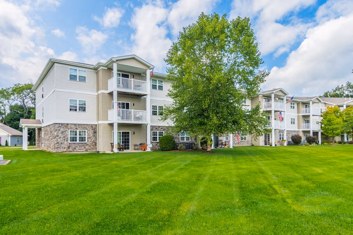 Exterior view of Schuyler Commons: multi-unit building with balconies and a lush green lawn.