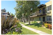 Exterior view of Heritage Park at Alta Loma showing walkway, lawn, trees, and a two-story building.