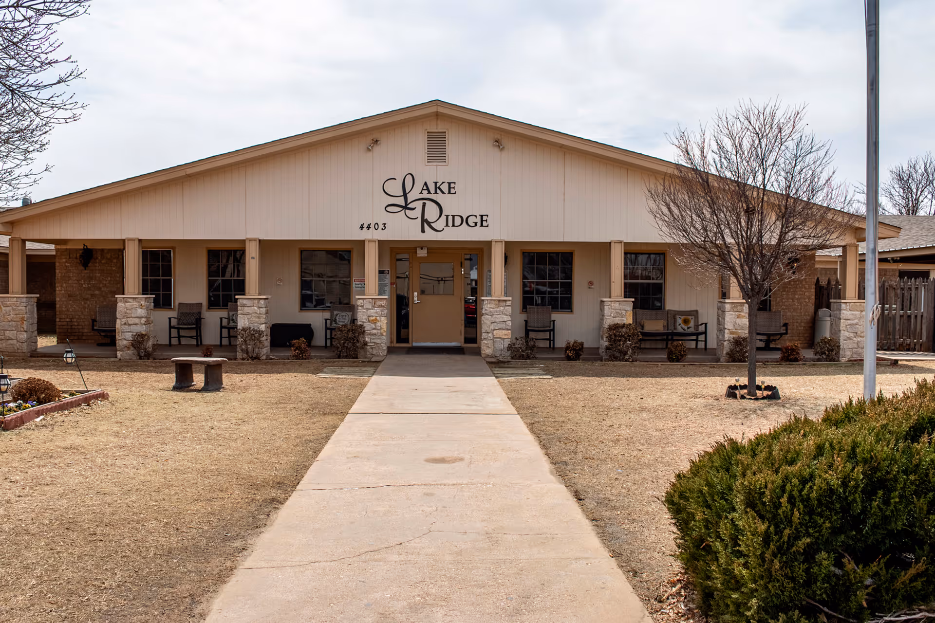 Front view of a single-story nursing facility with a central entrance and porch benches.