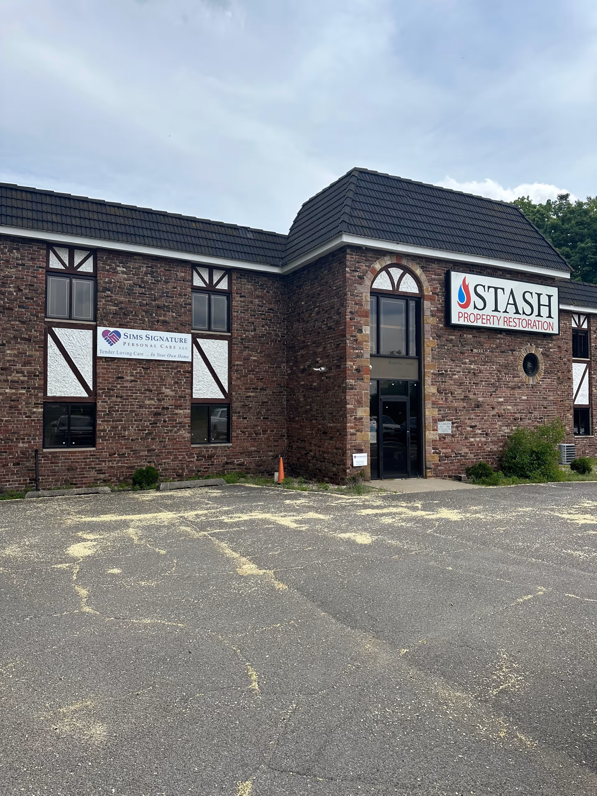 Brick storefront building with Sims Signature Personal Care and STASH Property Restoration signs.