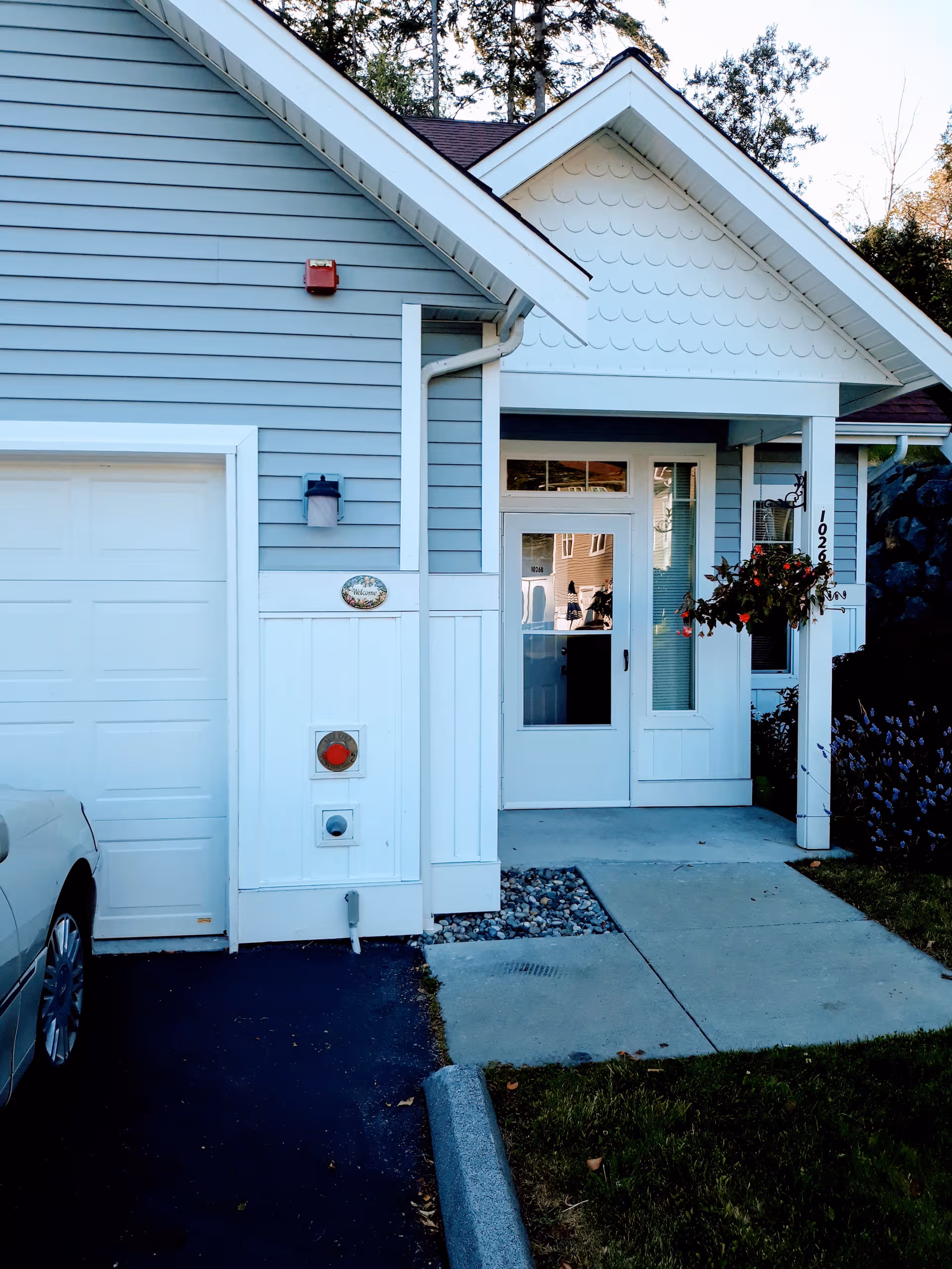 Front view of a light gray building entrance with a hanging planter.