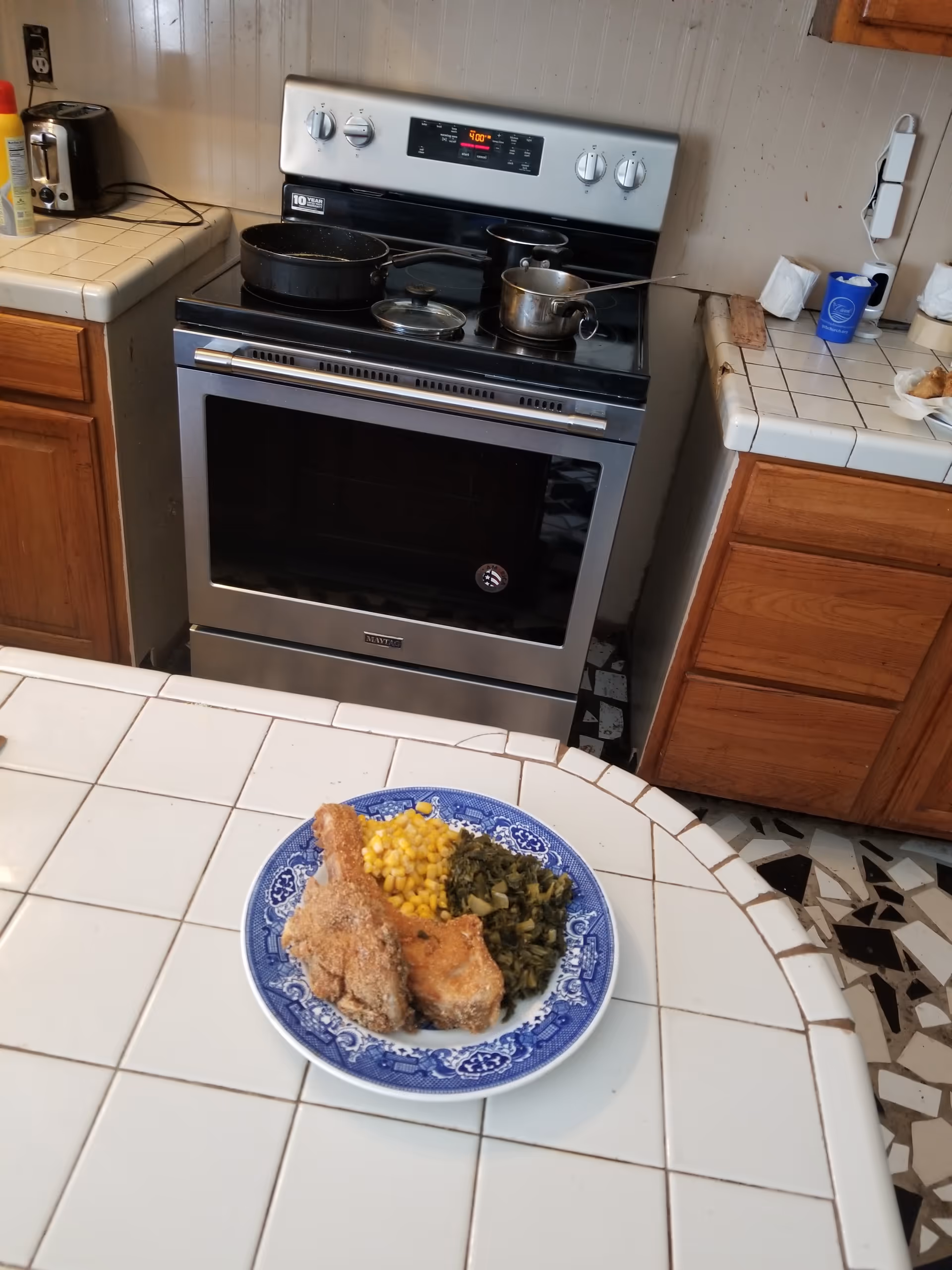 Stainless steel oven and stove in a kitchen with a plate of food on tile table.