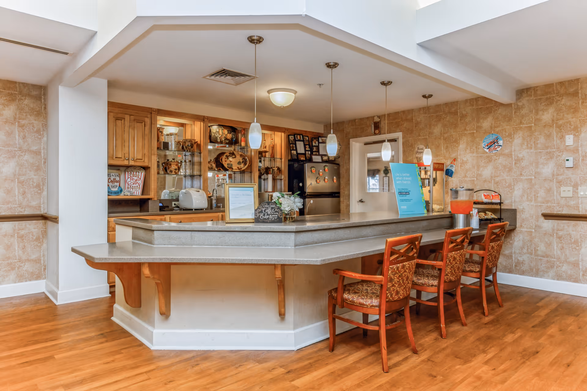 Indoor cafe-style counter with stools and serving area in a senior living facility.