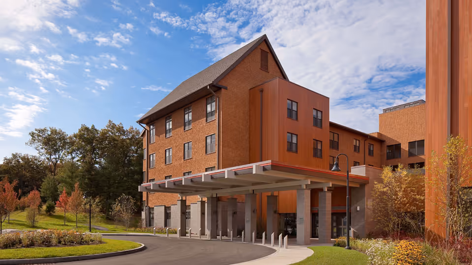 Brick senior living building with a covered entrance, curved driveway, and landscaped surroundings.