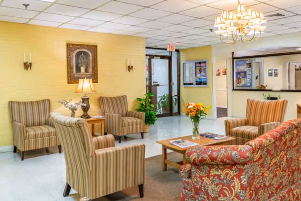 A cozy senior living lobby with striped chairs, a floral sofa, and a coffee table.