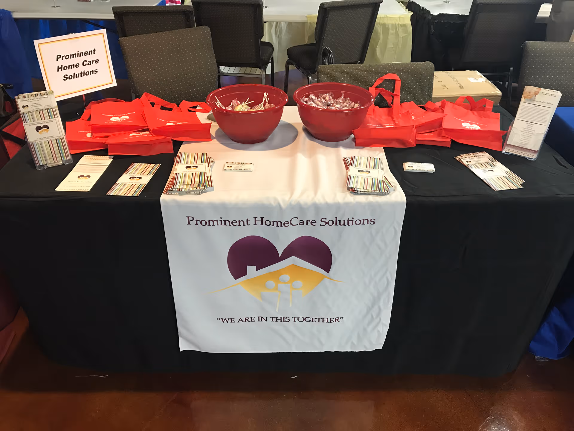 Prominent Home Care Solutions booth with red bags and brochures on a table