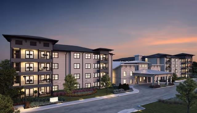 Exterior view of a multi-building senior living campus at dusk with landscaped driveway.
