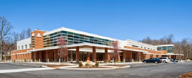Modern brick and glass medical center with a covered entrance and parking lot.