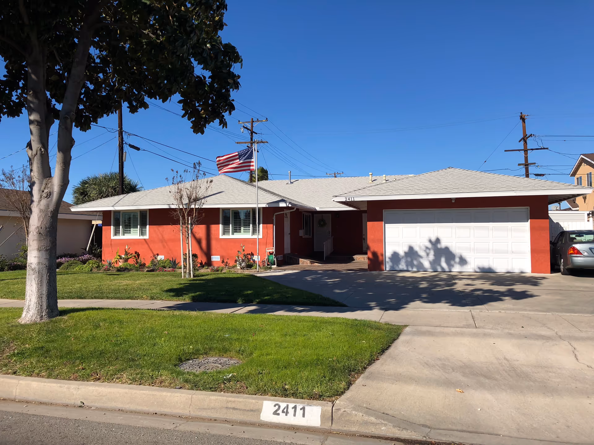 Red, single-story senior living facility front with a white garage, flag, and green lawn.