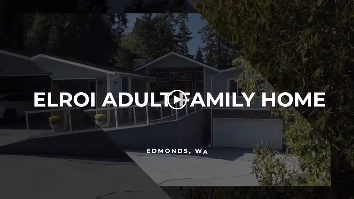Exterior view of a single-story residential building with a driveway and ramp, surrounded by trees and greenery, under a clear sky.