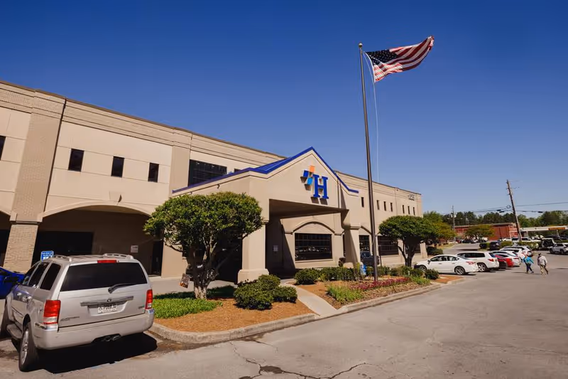 Exterior view of Harbin Clinic Home Infusion Therapy building with parking lot and flagpole