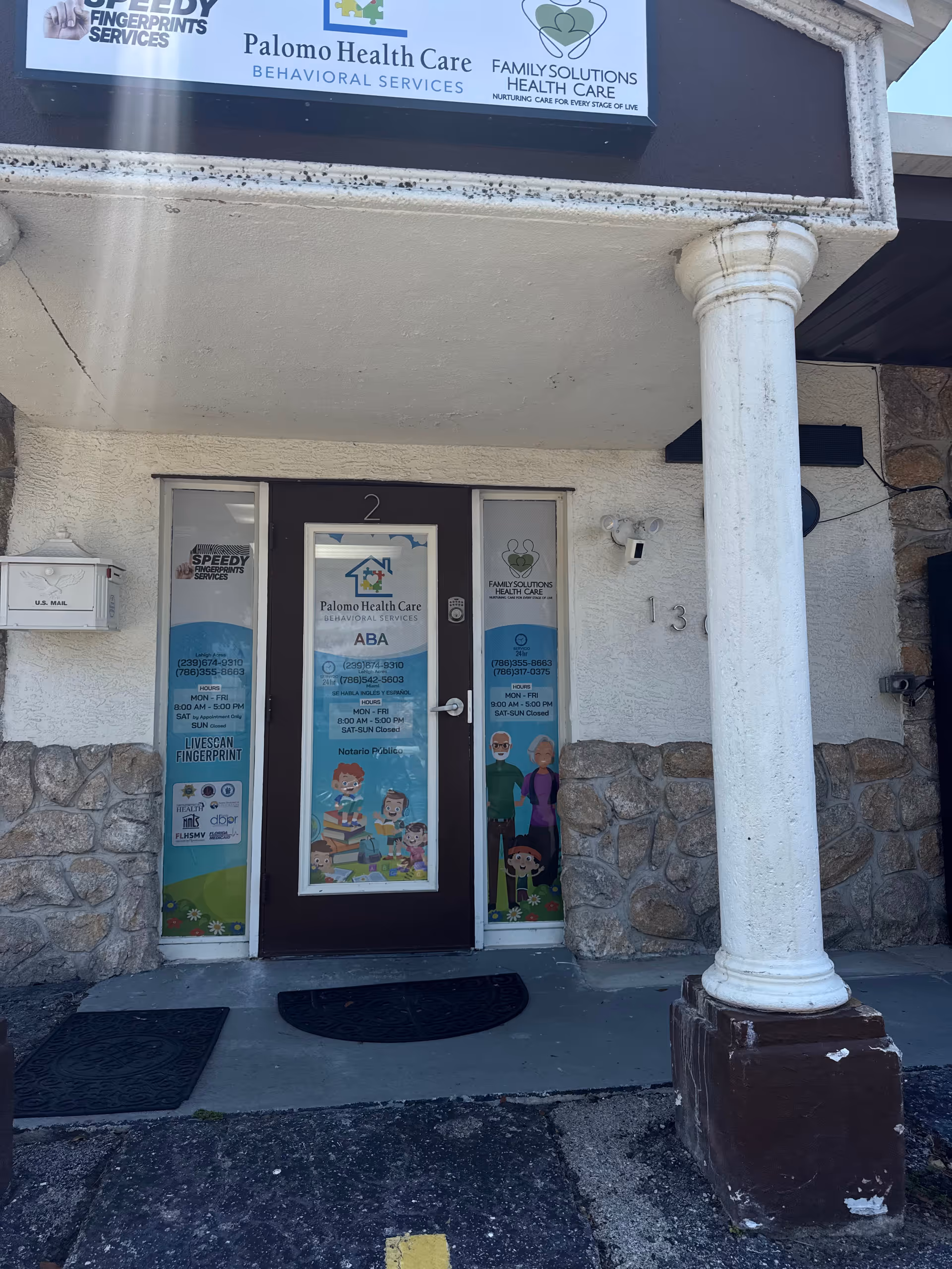 Front entrance of Palomo Health Care, showing signs, glass doors, and stone facade.