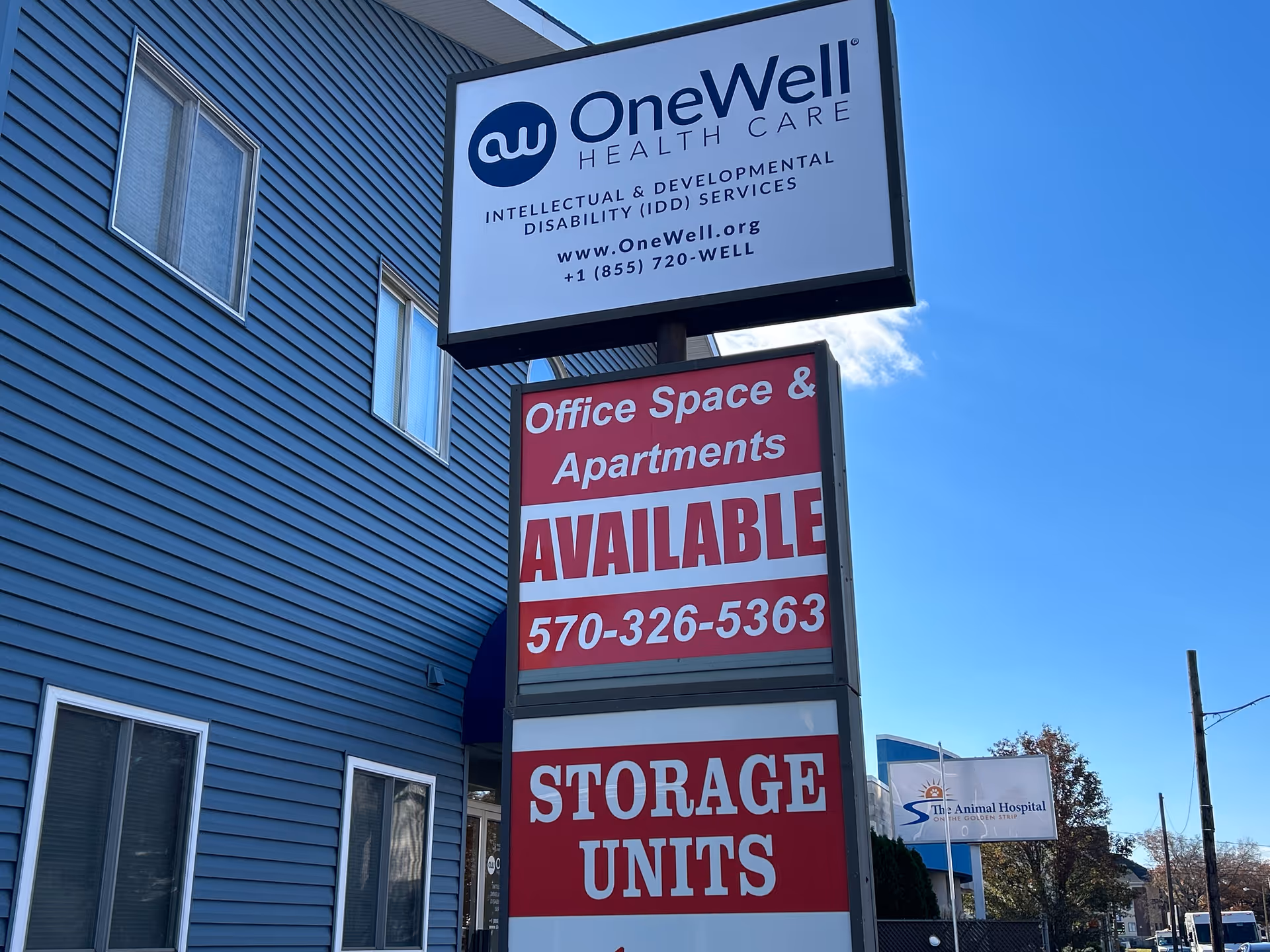 Blue building exterior with OneWell Health Care sign and red available space signs.