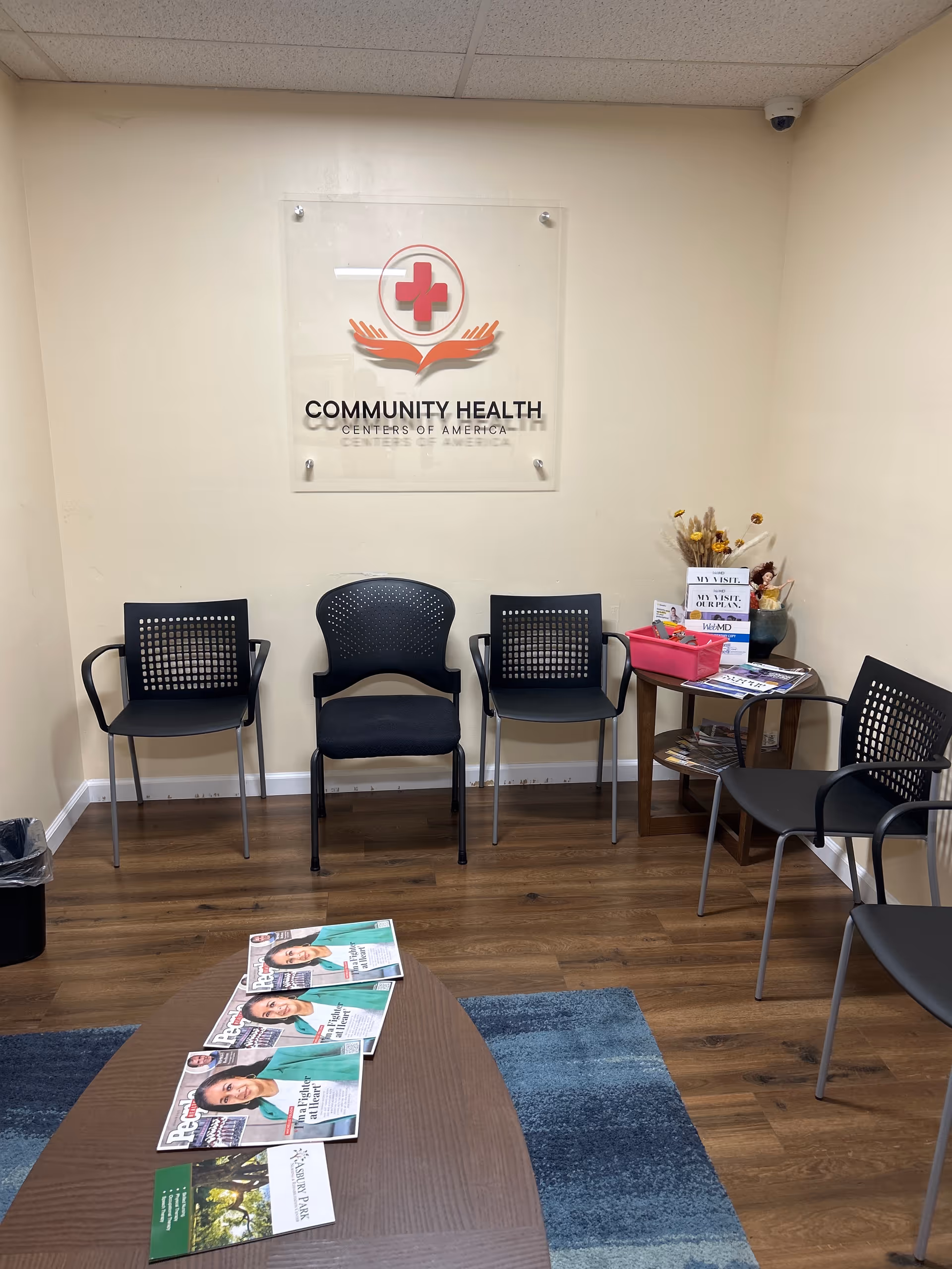 A waiting area with black chairs and a Community Health Centers of America sign.