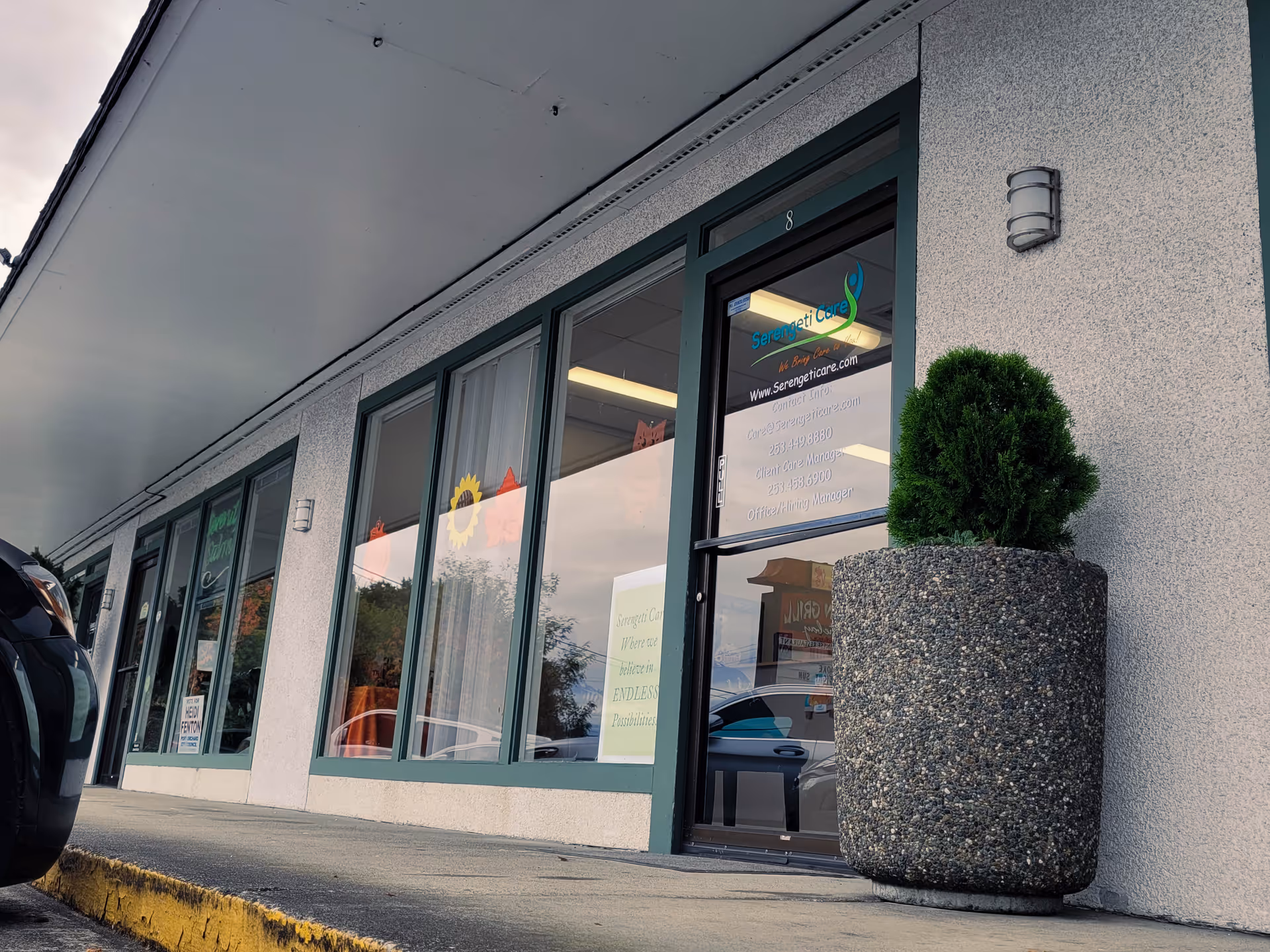Exterior view of Serengeti Care facility storefront with glass doors, windows, and a planter.