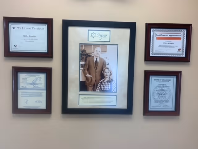 Wall display of multiple framed certificates and a central photo of a man with a child.