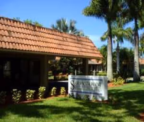 Exterior of Sarasota Point Rehabilitation Center with a tiled roof and palm trees.