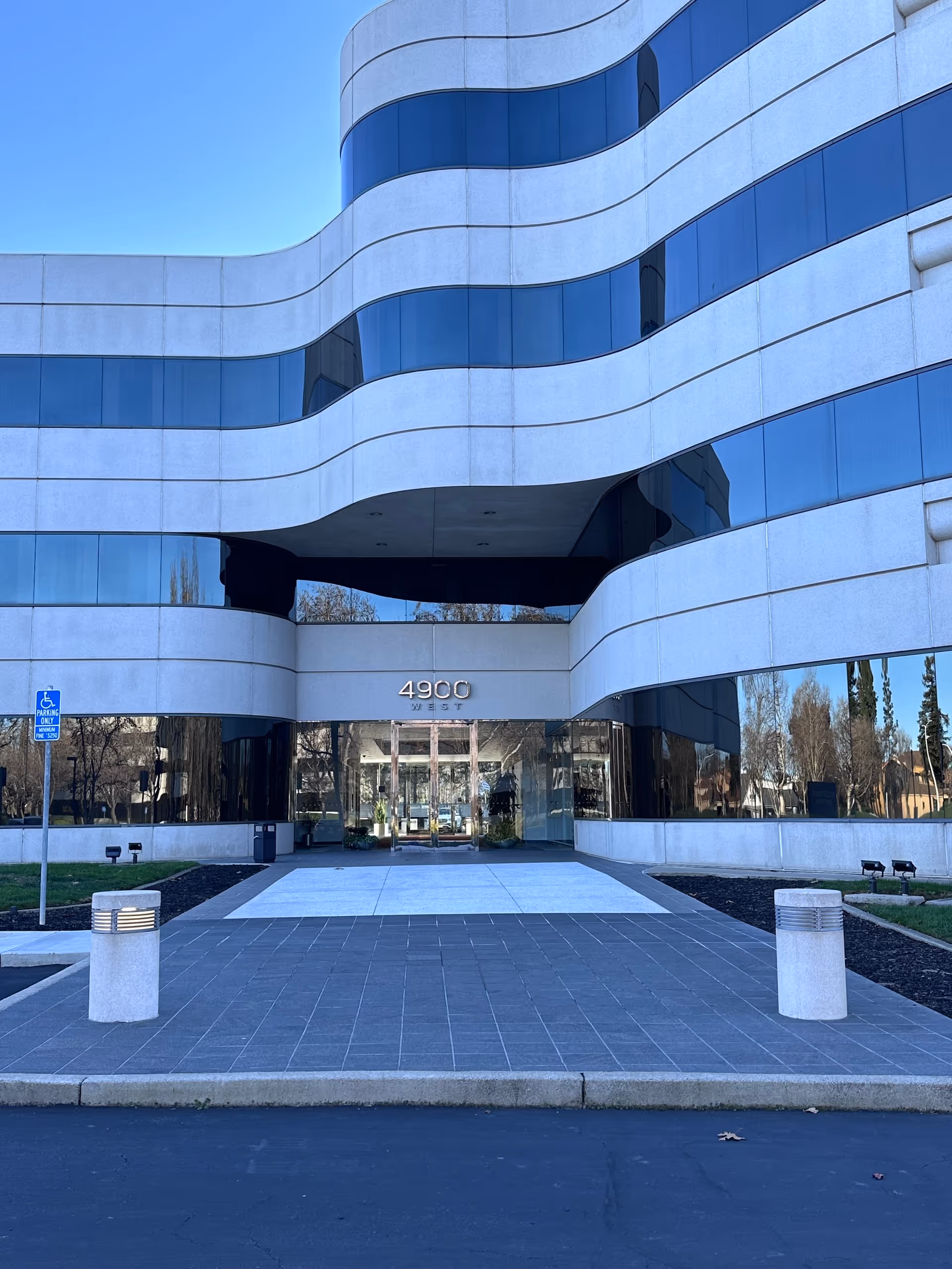 Modern curved glass-front building with white bands and a central entrance.