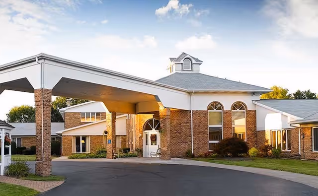 Front view of Symphony Assisted Living entrance with brick building and covered driveway.