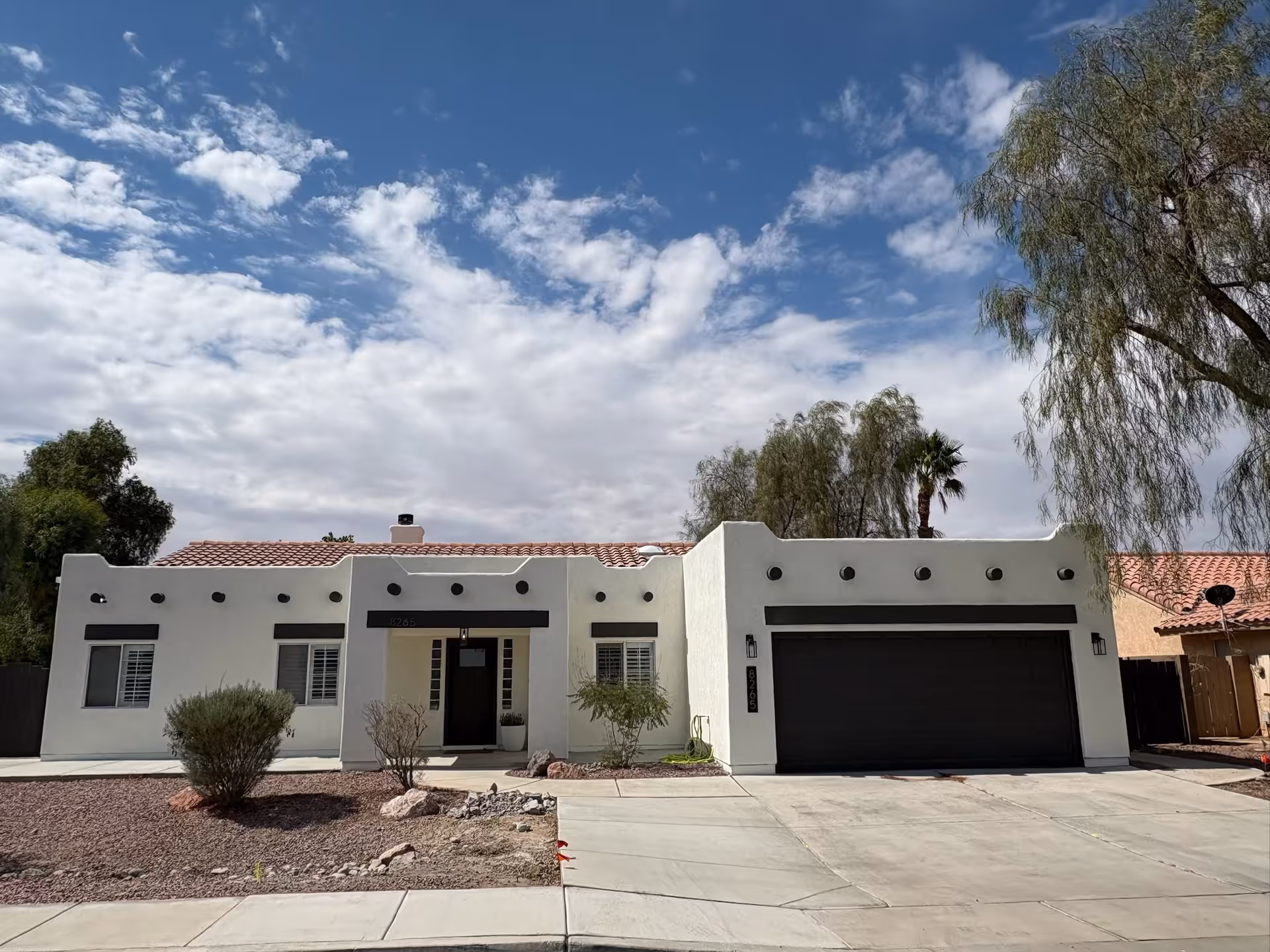 White stucco assisted living home exterior with a two-car garage and desert landscaping.