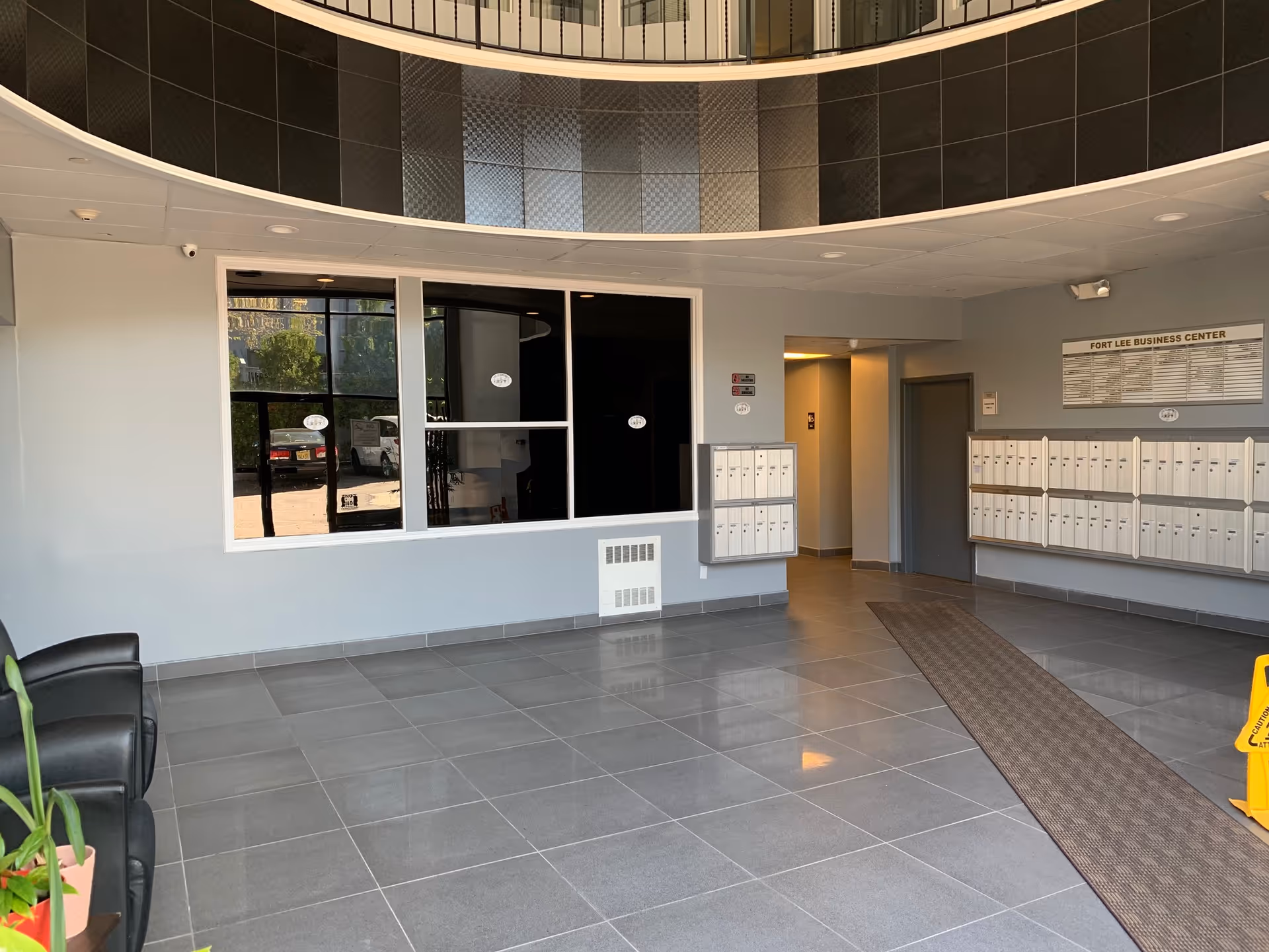 Modern interior lobby with mailboxes, a large window, tiled floor, and curved ceiling.