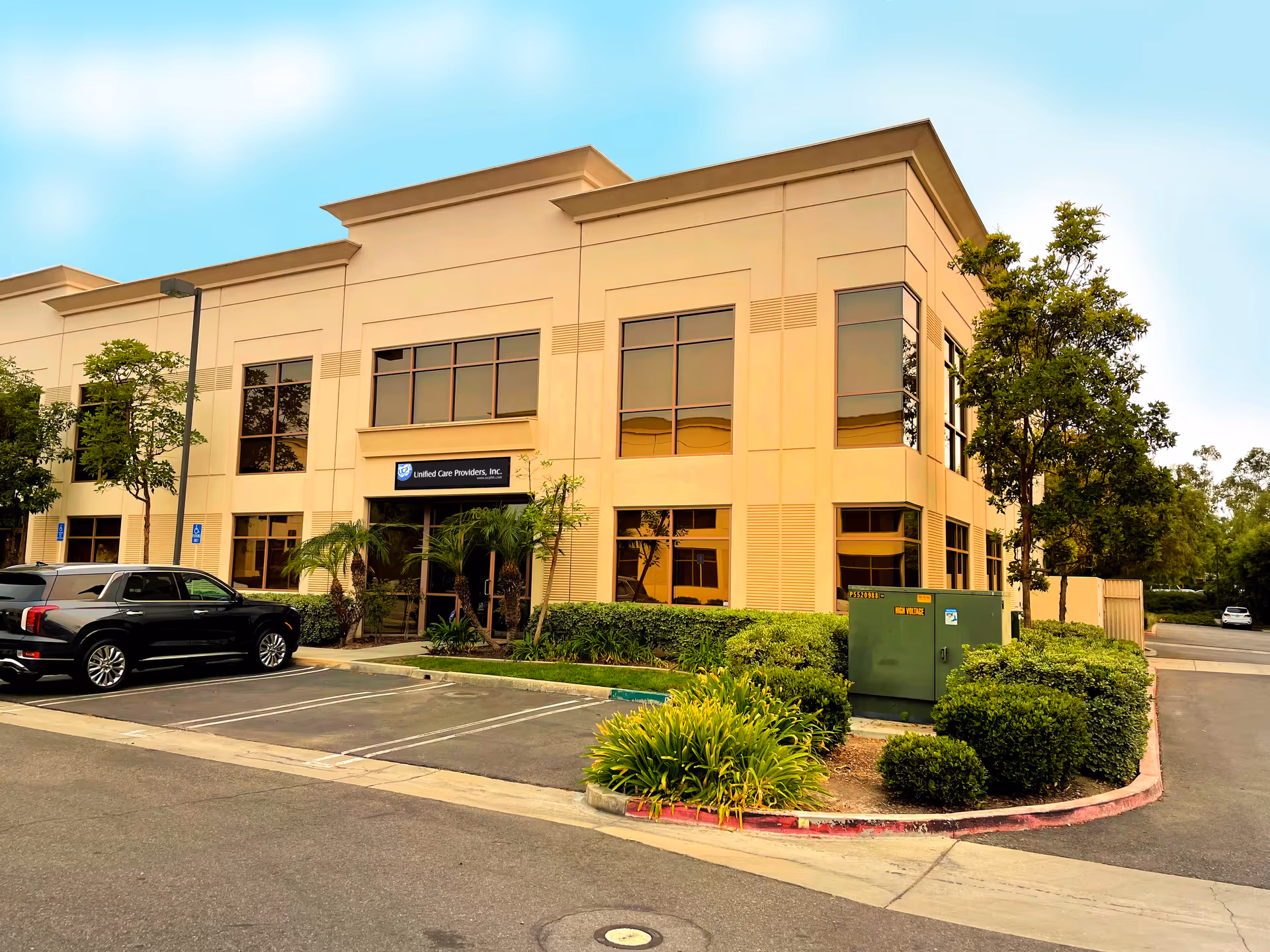 Beige two-story facility exterior with parking lot and landscaped entrance.