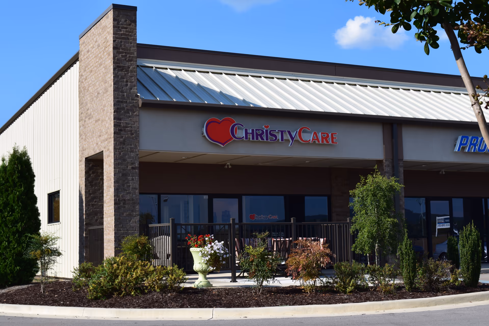 Front exterior of ChristyCare facility featuring sign, glass storefront, and outdoor seating.