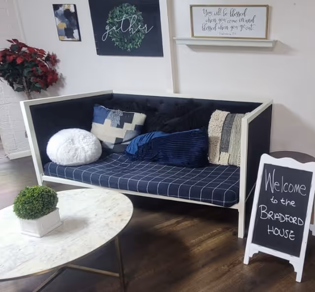 A navy plaid sofa with cushions in a cozy lobby area at Bradford House, welcome sign.