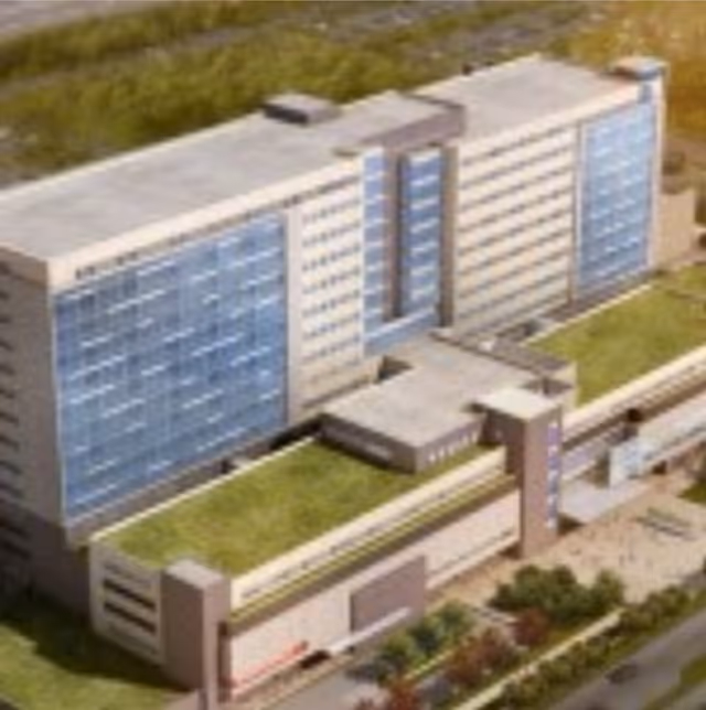 Aerial view of a modern multi-story care facility with glass walls and landscaped grounds.