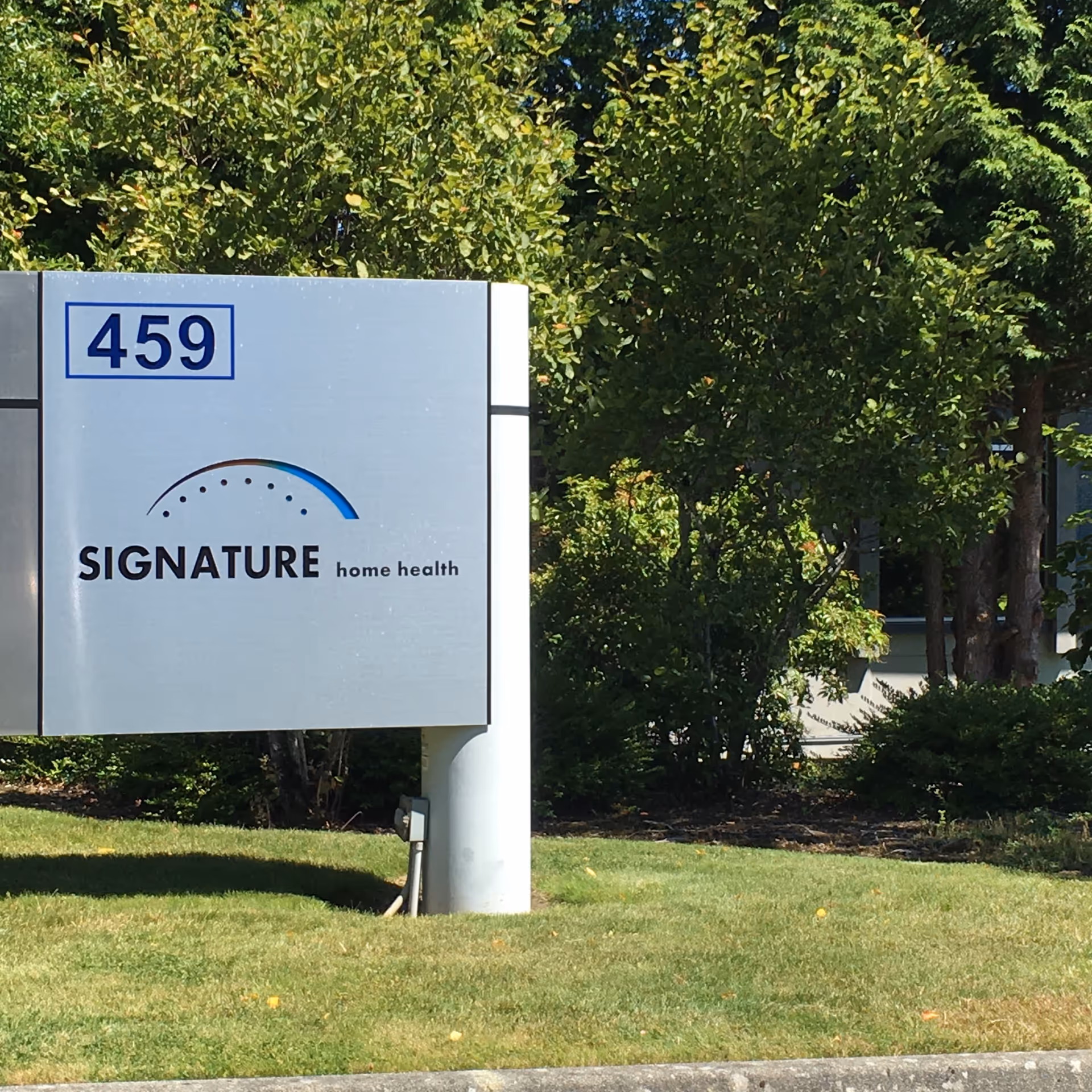 A large exterior sign for Signature Home Health displaying 459 near trees.