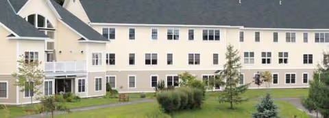 Front exterior of Westview Meadows at Montpelier, cream-colored building with multiple windows, lawn and trees.