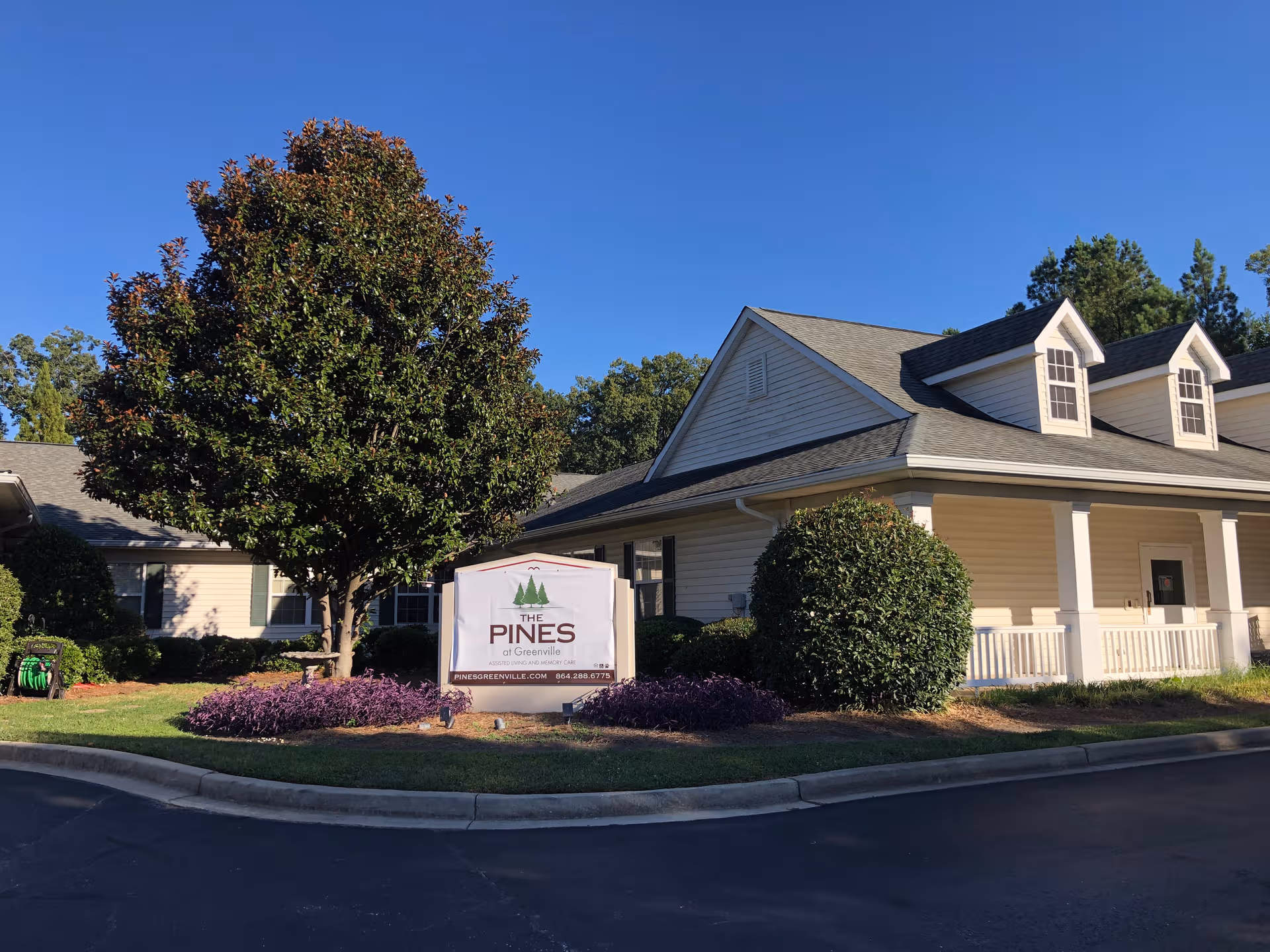 Exterior view of The Pines at Greenville with sign and landscaped grounds.