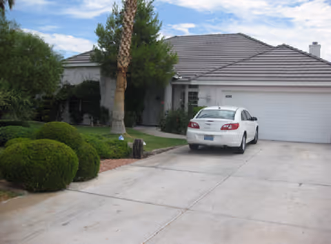 Front exterior of a single-story senior living facility with a white car in the driveway.