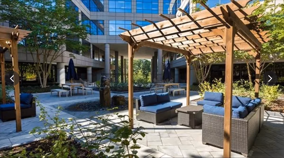 Arya Home Healthcare outdoor courtyard with blue-cushioned seating and wooden pergolas.