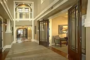 Spacious, well-lit corridor in a senior living facility with open doorways to lounge areas.