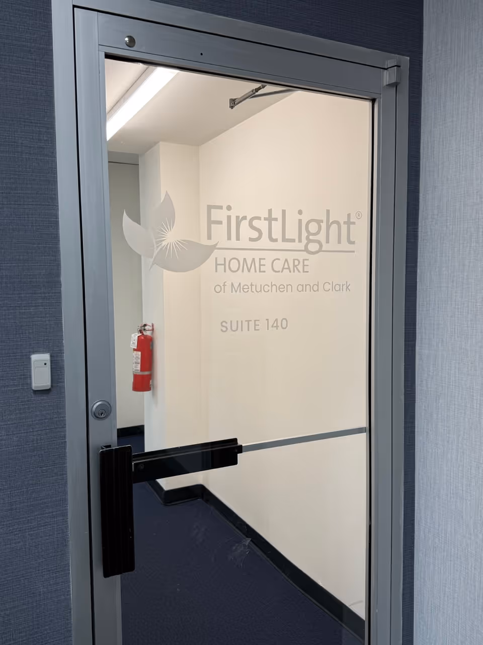 Glass door with FirstLight Home Care logo; interior hallway visible.