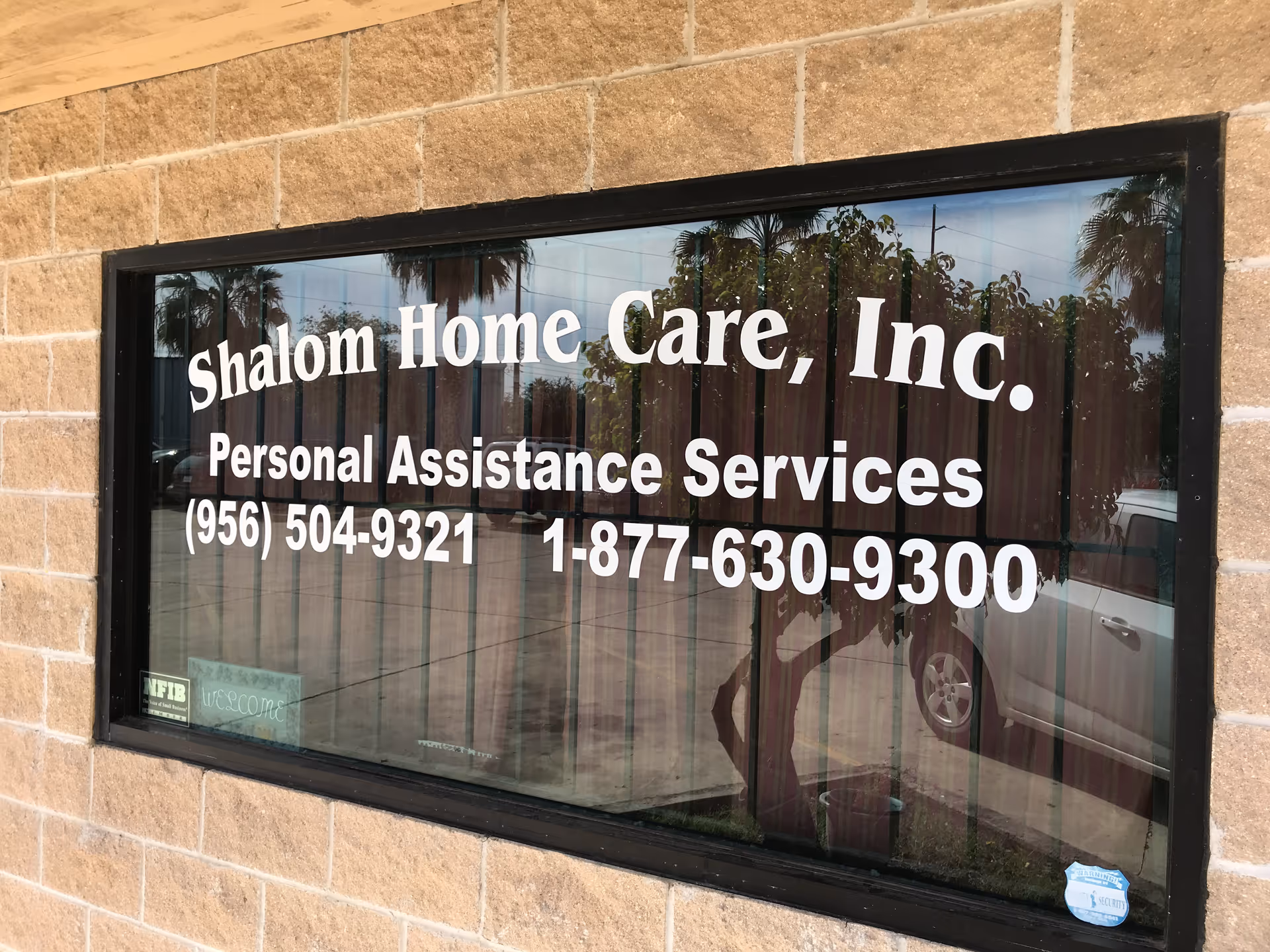 Front window sign for Shalom Home Care, Inc. on brick building.
