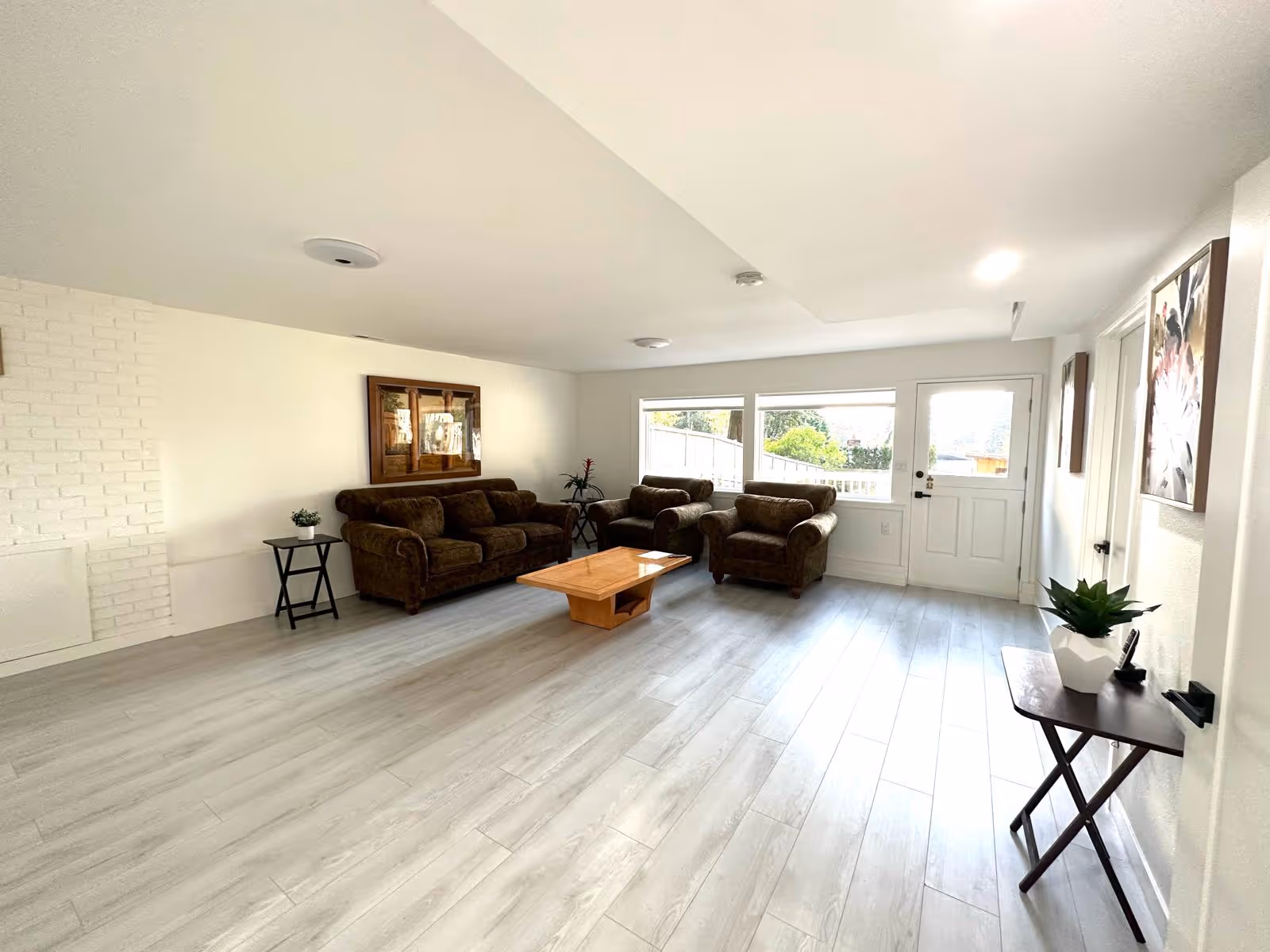 Bright living room with brown sofas, chairs, coffee table, and large windows.