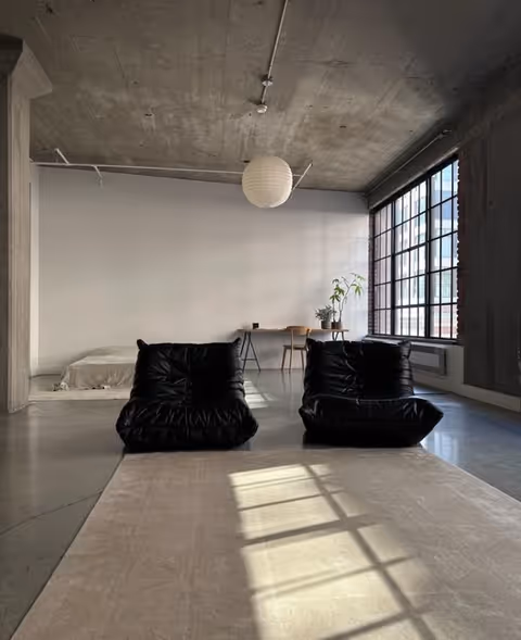 Open loft interior with concrete ceiling, large windows, and black bean bag chairs.