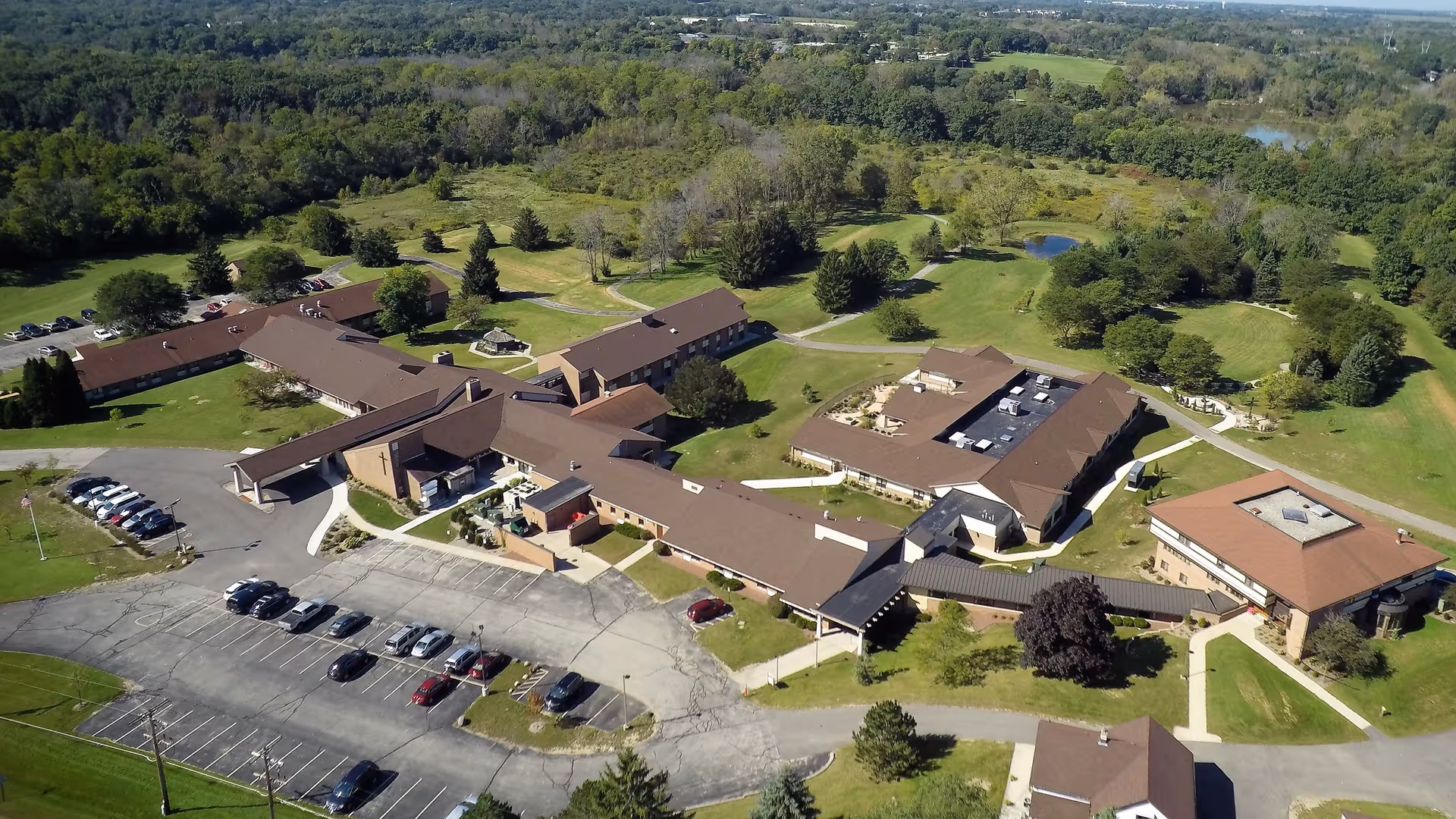 Aerial view of a brown-roofed senior living campus with parking and green grounds.