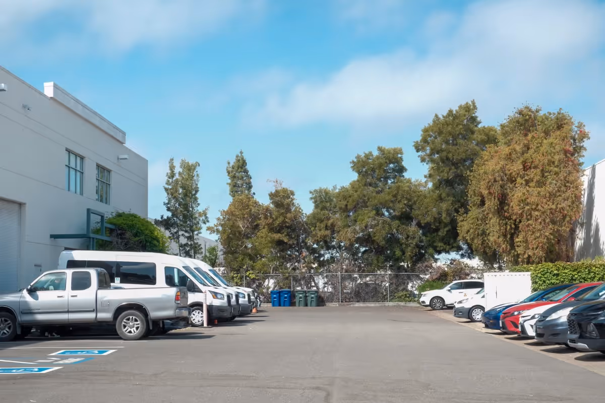 Exterior view of a senior living facility parking lot with parked vehicles and trees