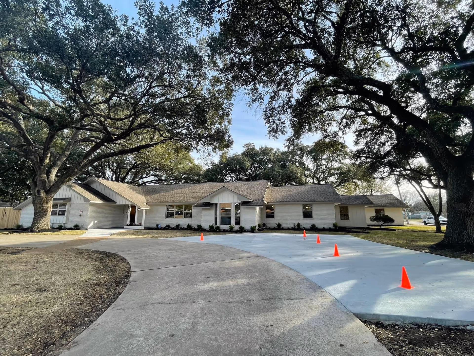Single-story senior living facility exterior with a curved driveway and large oak trees.
