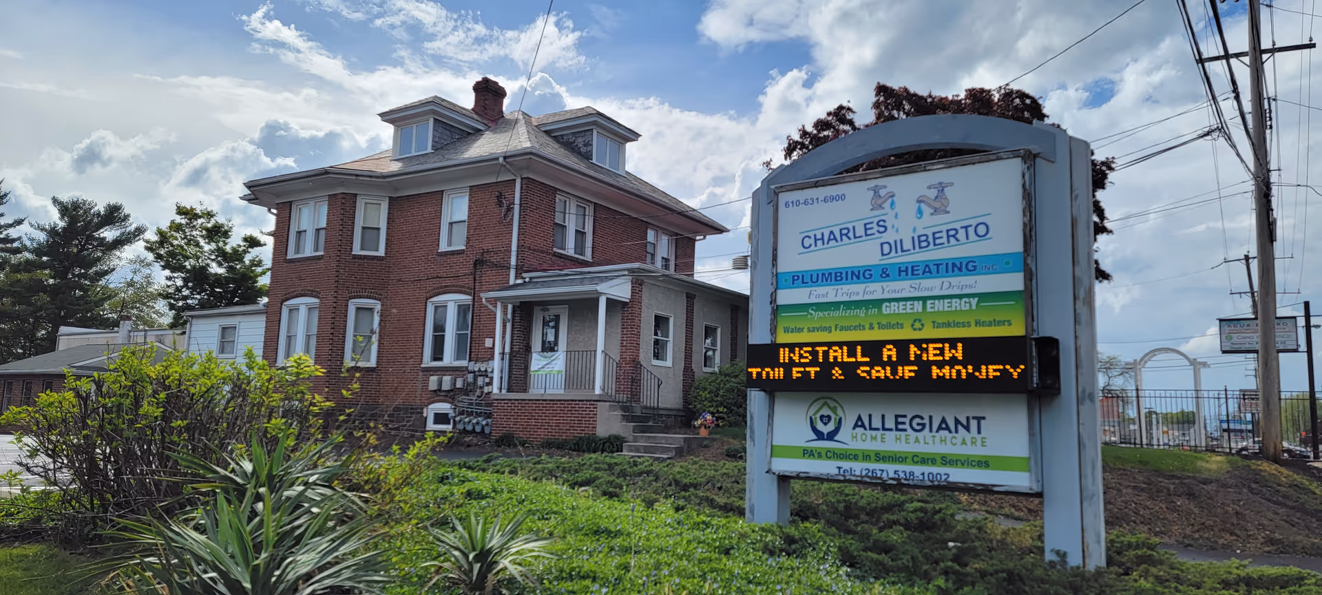 A brick two-story building with an Allegiant Home Healthcare sign and greenery in front.