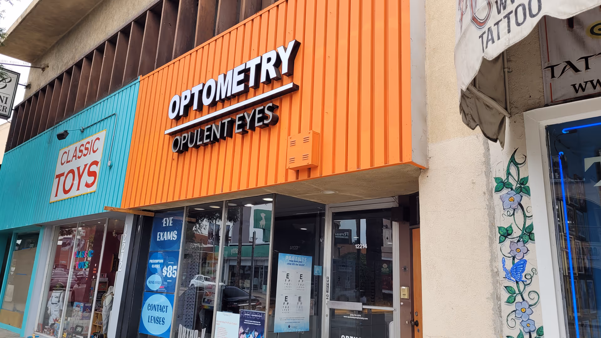 Colorful storefronts on a street; Optometry sign says Opulent Eyes.